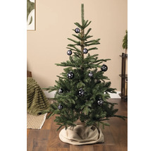 Kerstboom in een lichte woonkamer, versierd met kerstballen met een sneeuwvlokkenpatroon.