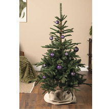 Een kerstboom versierd met paarse kerstballen met een wit sneeuwvlokpatroon, staand op een houten vloer.