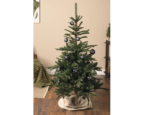 Kerstboom in een lichte woonkamer, versierd met kerstballen met een sneeuwvlokkenpatroon.