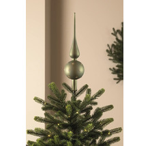Groene glazen kerstboompiek met sterrendecor, geplaatst op de top van een verlichte kerstboom.
