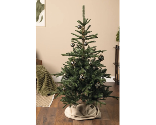 Gedecoreerde kunstkerstboom met donkere kerstballen met ruitpatroon in een woonkamer met houten vloer.