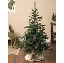 Kunstkerstboom met gedecoreerde kerstballen in een sfeervolle woonkamer met houten vloer en kerstversiering.