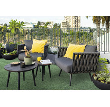 Moderne loungeset voor buiten op een dakterras met twee grijze fauteuils, gele kussens, bijzettafels en diverse plantenbakken op kunstgras.