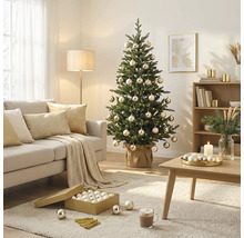 Gedecoreerde kerstboom met kerstballen en lampjes in een lichte woonkamer met bank, salontafel en vloerkleed.