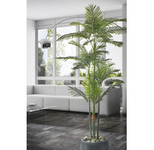 Kunstpalm in pot in een lichte, moderne woonkamer met witte bank, glazen tafel en een booglamp voor een raam.