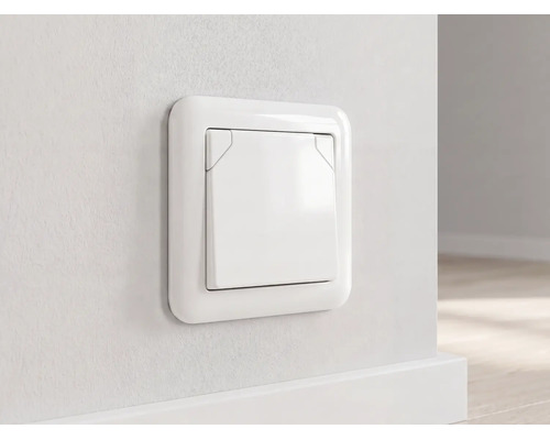 Wit inbouwstopcontact met klapdeksel, gemonteerd op een muur boven een plint.