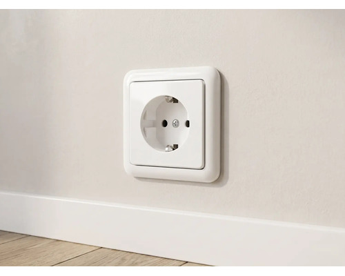 Wit geaard stopcontact met afgerond frame gemonteerd op een muur boven een plint.
