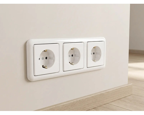 Witte 3-voudige geaarde wandcontactdoos met afdekraam, horizontaal gemonteerd op een muur boven een plint in houtoptiek.