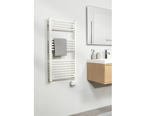 Moderne badkamer met witte elektrische handdoekradiator, grijze handdoek, houten wastafelmeubel met wasbak en een grote spiegel.