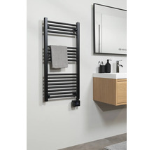 Zwarte handdoekradiator met digitale thermostaat in de badkamer naast een houten wastafelmeubel met wasbak en spiegel.