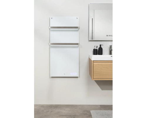 Moderne infrarood badkamerverwarming van wit glas met twee roestvrijstalen handdoekstangen naast een licht houten wastafelmeubel.