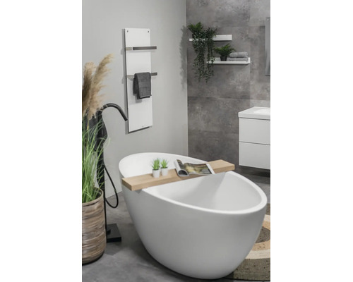 Moderne, lichte badkamer met vrijstaand wit bad, zwarte staande kraan, houten badplank en witte handdoekradiator aan de wand.