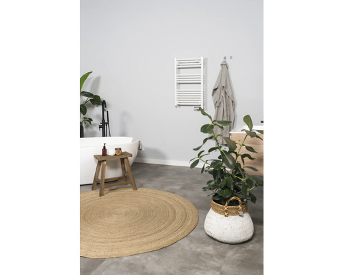 Moderne lichte badkamer met vrijstaand bad, zwarte vrijstaande kraan, witte handdoekradiator, houten krukje en rond jute vloerkleed.