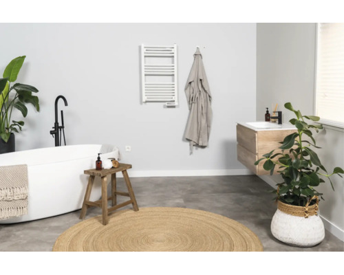 Moderne, lichte badkamer met vrijstaand bad, houten wastafelmeubel, witte handdoekradiator en rond jute vloerkleed.