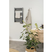 Zwarte elektrische handdoekradiator in een moderne badkamer met handdoek, badjas en wastafel.