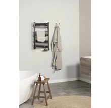 Moderne, lichte badkamer met een zwarte handdoekradiator aan de muur, een witte badkuip, een houten krukje en een badjas.