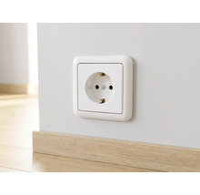 Geaard stopcontact in wit, gemonteerd op een lichte wand boven een plint met houtlook.