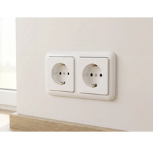 Dubbele wandcontactdoos met randaarde horizontaal gemonteerd op een muur boven een plint.