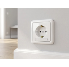 Schuko stopcontact met tekstveld gemonteerd op een wand boven een plint.