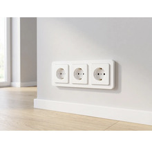 Drievoudig stopcontact horizontaal gemonteerd op een muur boven een plint in een moderne kamer met houten vloer.