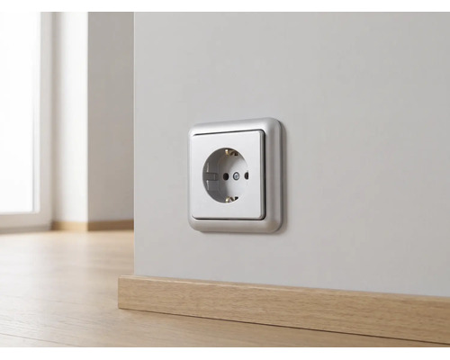 Zilverkleurige wandcontactdoos gemonteerd op een lichte muur boven een houten plint.