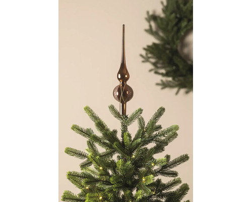 Glazen kerstboompiek met glitterdecoratie op de top van een kerstboom met verlichting.