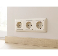 Drievoudige wandcontactdoos met randaarde in een frame gemonteerd op de muur boven een plint.
