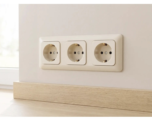 Drievoudige wandcontactdoos met randaarde in een frame gemonteerd op de muur boven een plint.
