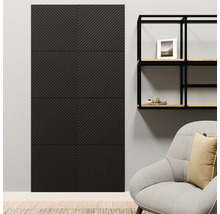 Antracietkleurig wandpaneel met visgraatpatroon op een lichte muur naast een zwart metalen rek en een fauteuil in een moderne woonkamer.