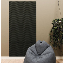 Zwart akoestisch paneel met horizontale golfstructuur op een beige muur, gecombineerd met een grijze zitzak en een hangplant.