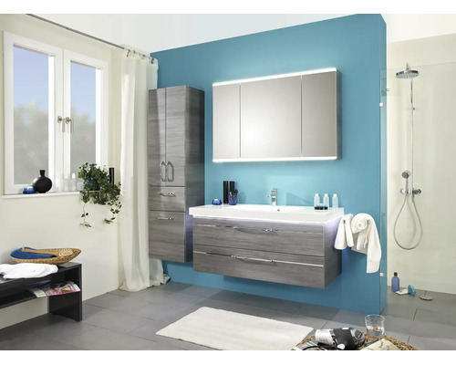 Moderne badkamer met grijs wastafelmeubel, driedeurs spiegelkast met verlichting, kolomkast en inloopdouche tegen een blauwe wand.