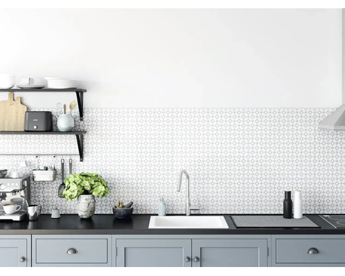 Moderne, lichte keuken met een achterwand met geometrisch patroon, witte inbouwspoelbak, chromen kraan en grijze onderkasten.