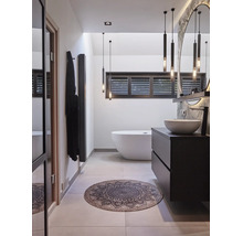 Moderne badkamer met vrijstaand ligbad, donker badkamermeubel en ronde badmat met ornamenten.