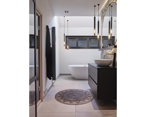 Moderne badkamer met vrijstaand ligbad, donker badkamermeubel en ronde badmat met ornamenten.