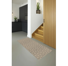 Moderne woonruimte met een vloerkleed met geometrisch patroon, grijze vloer, zwarte keuken en verlichte houten trap.