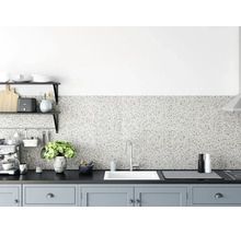 Keukenachterwand met terrazzo-uiterlijk in een modern ingerichte keuken met donker werkblad, witte gootsteen en lichtgrijze kasten.