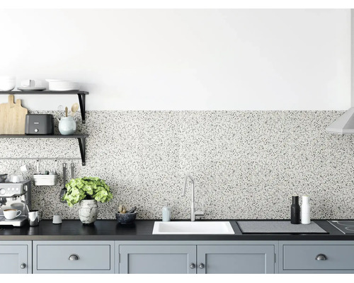Keukenachterwand met terrazzo-uiterlijk in een modern ingerichte keuken met donker werkblad, witte gootsteen en lichtgrijze kasten.