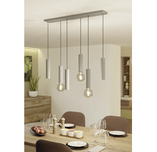 Moderne hanglamp met zes lichtpunten, geribbelde cilindrische houders en grote bolvormige lampen boven een gedekte eettafel.