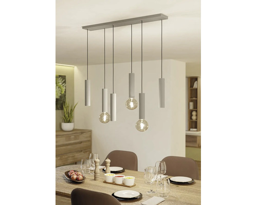 Moderne hanglamp met zes lichtpunten, geribbelde cilindrische houders en grote bolvormige lampen boven een gedekte eettafel.