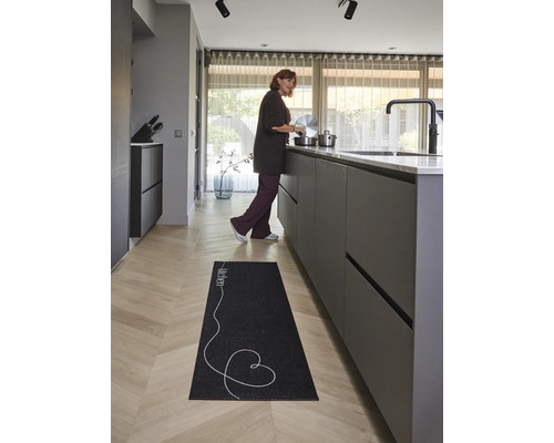 Zwarte keukenloper met tekst Kitchen en hart op lichte houten vloer in een moderne, lichte keuken.