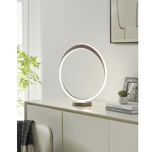 Moderne LED-tafellamp in de vorm van een ring op een dressoir. Lichte kamer met een plant, boeken en een fotolijst.