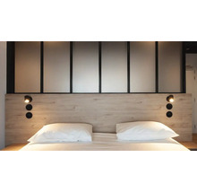 Moderne slaapkamer met hoofdbord in lichte houtlook, zwarte leeslampen, witte kussens en een glazen scheidingswand.