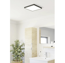 Lichte badkamer met vierkante LED-plafondlamp, modern wastafelmeubel, hoge kast met houtlook en kamerplant.
