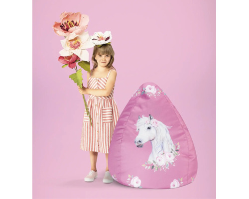 Kind naast een zitzak met paardenprint en bloemenmotief.