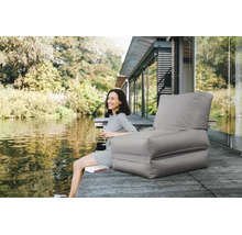 Grijze outdoor zitzak in de vorm van een fauteuil op een houten steiger aan een meer. Tuinloungemeubilair voor buiten.