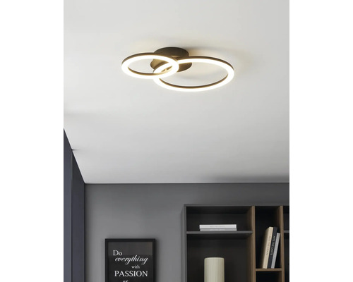 Moderne LED-plafondlamp met twee lichtgevende ringen in een lichte, georganiseerde kamer boven een plank.
