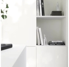 Moderne witte wandkast in minimalistisch ontwerp met boeken en decoratieve figuren.