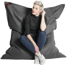 Een vrouw zit op een grote, antracietkleurige Big Foot zitzak van slijtvast materiaal.