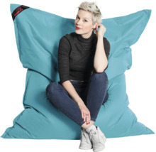 Een persoon zit op een grote, turquoise Big Foot zitzak van duurzaam materiaal om de grootte en het comfort te tonen.