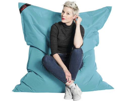 Een persoon zit op een grote, turquoise Big Foot zitzak van duurzaam materiaal om de grootte en het comfort te tonen.